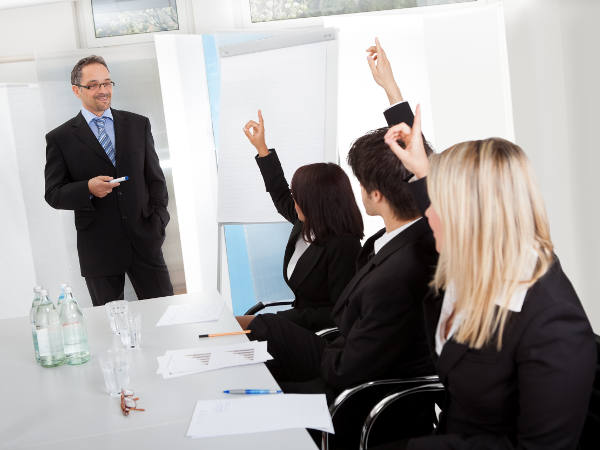 Group of business people at presentation raising hands in the office