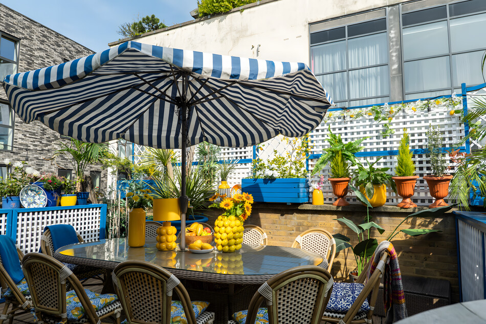 Colourful outdoor terrace with dining table, parasol and potted plants