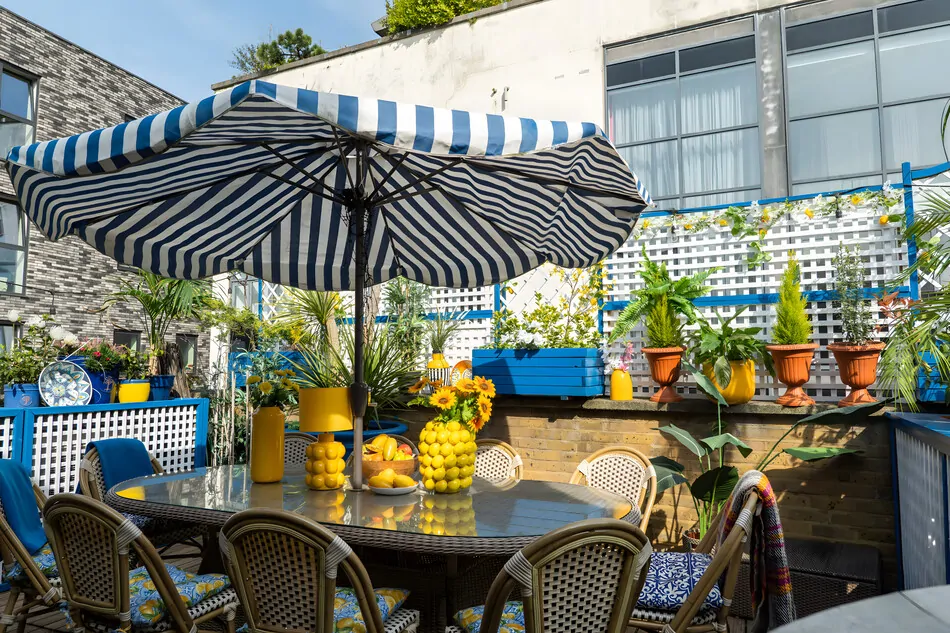 Colourful outdoor terrace with dining table, parasol and potted plants