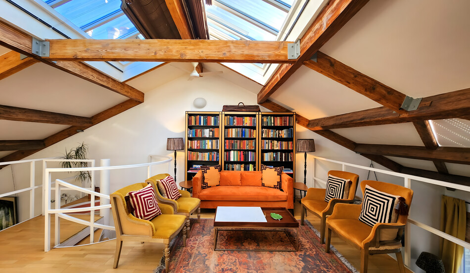 Stylish loft living room with exposed beams, skylights and cosy seating